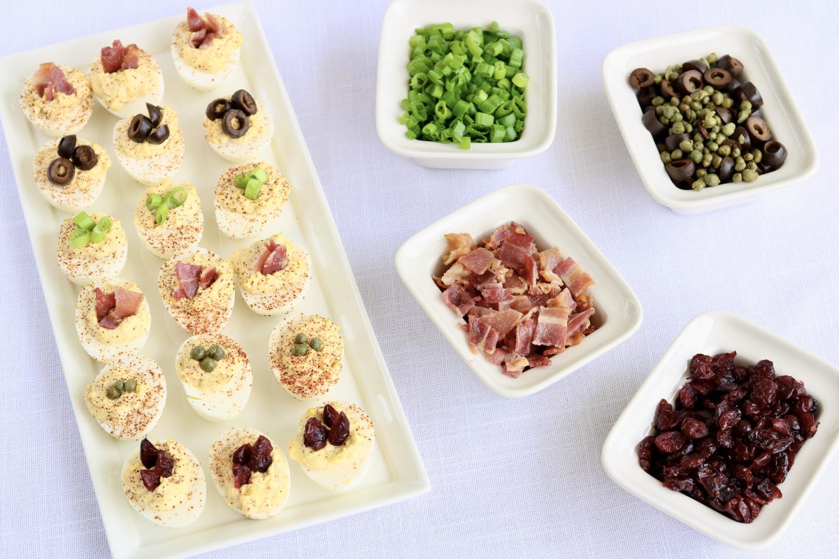 Deviled eggs topped with bacon, chives, cranberries, black olives and capers